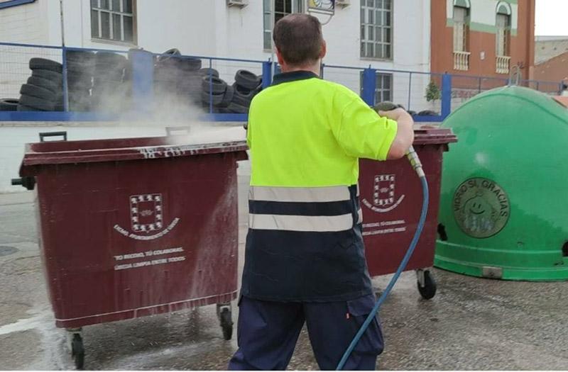 Un operario municipal limpia los contenedores de residuos.