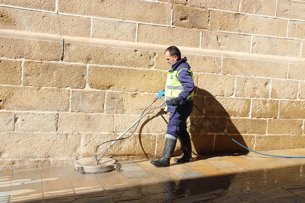 Un empleado municipal del Servicio de Limpieza elimina la cera derramada en la calle tras la Semana Santa.